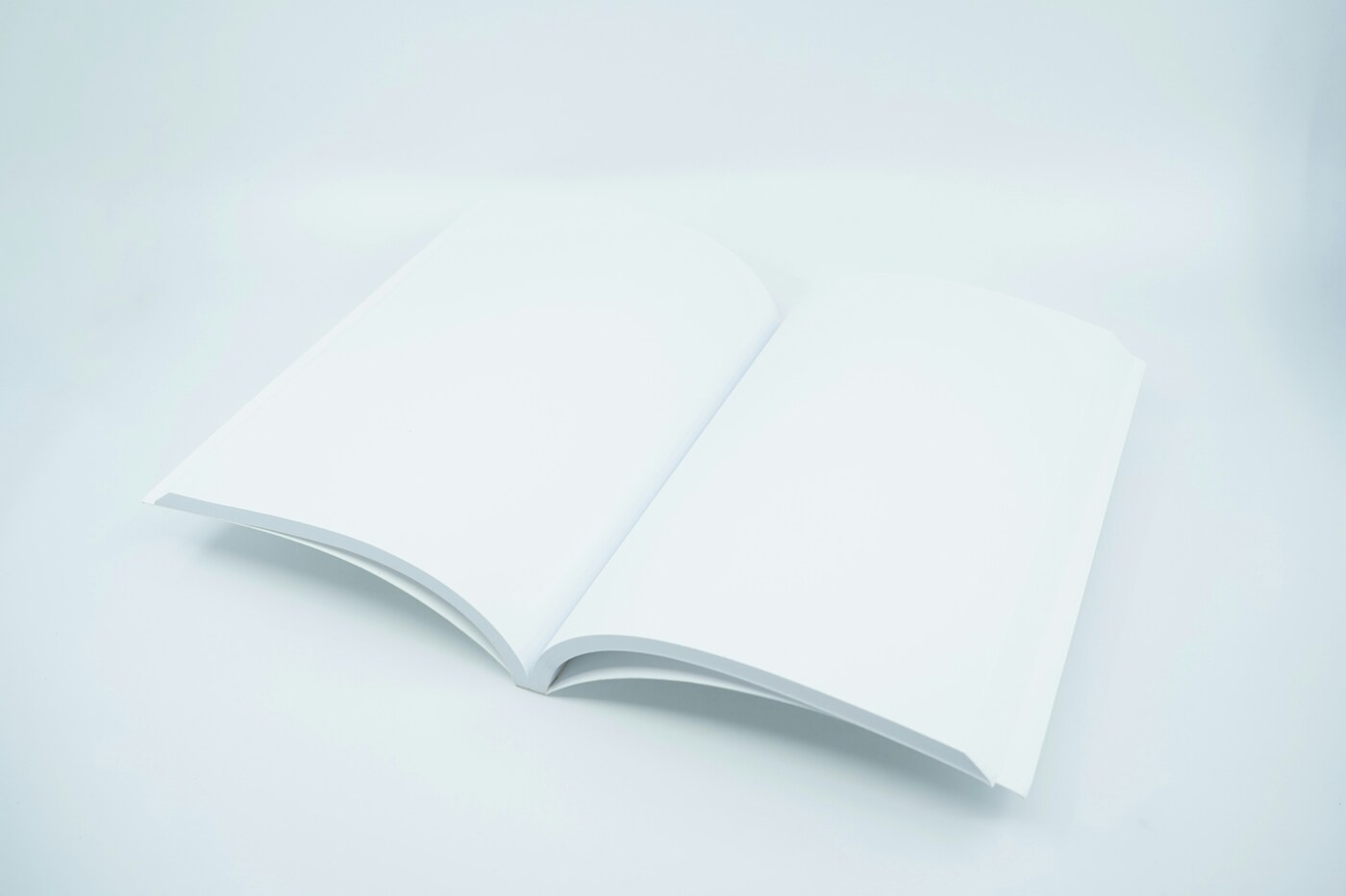 A blank white book lying open on a pale blue surface