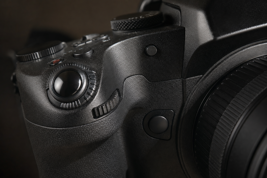 Detail shot of camera controls and grip, dramatic side lighting, macro feel, no text