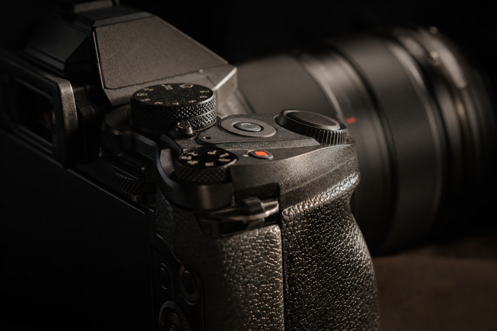 Detail shot of camera controls and grip, dramatic side lighting, macro feel, no text