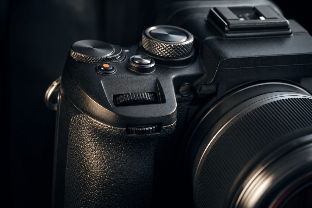 Detail shot of camera controls and grip, dramatic side lighting, macro feel, no text