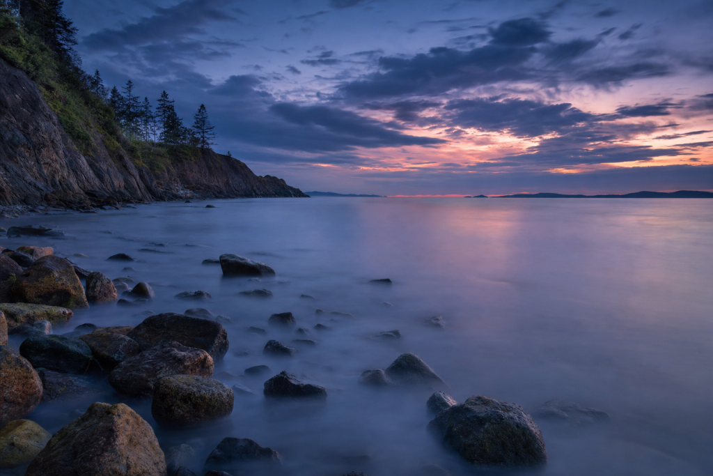Long-exposure coastal landscape at blue hour, silky water, dramatic sky