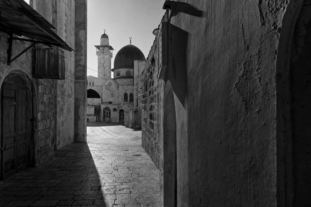 Black-and-white style street composition with strong geometric shadows, high contrast, decisive moment feel