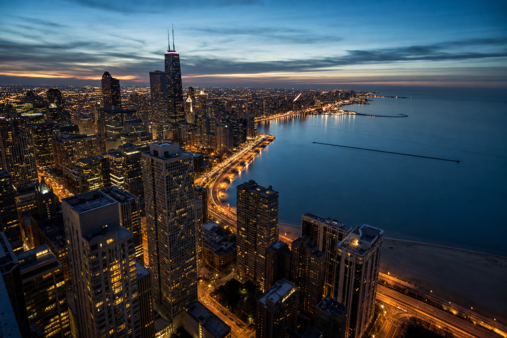 Atmospheric high-vantage view of Chicago during blue hour, glowing city lights, subtle motion blur in traffic