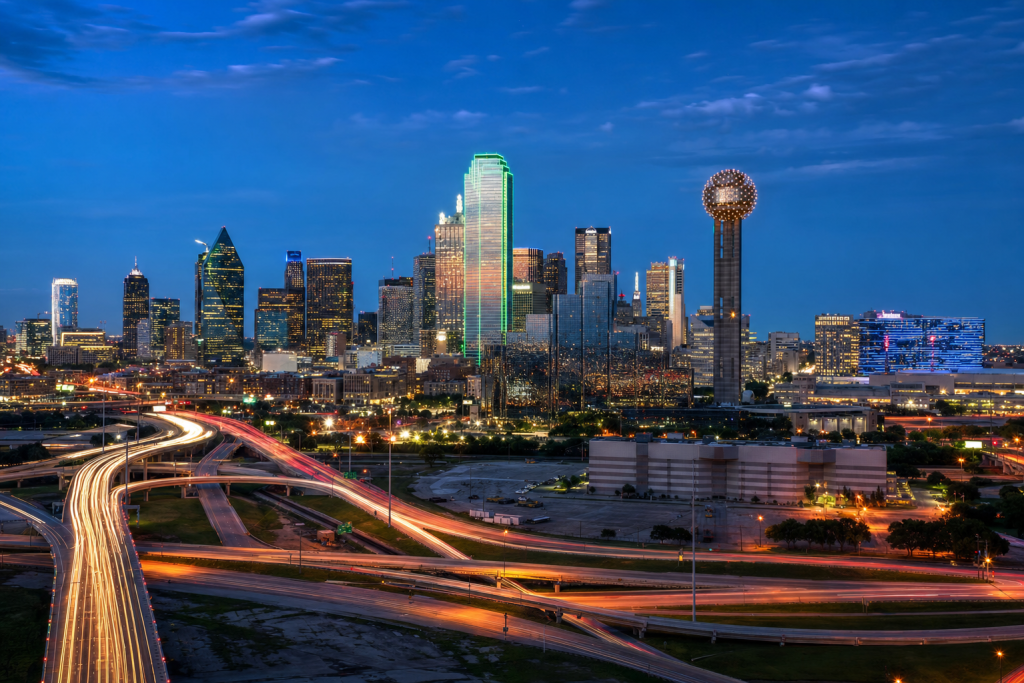 High-vantage view of Dallas during blue hour, glowing city lights, subtle motion blur in traffic