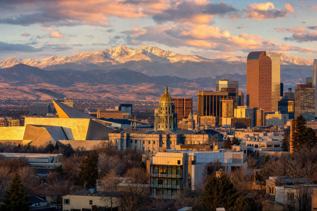 Wide-angle cinematic skyline of Denver at golden hour, iconic landmarks visible, dramatic warm light