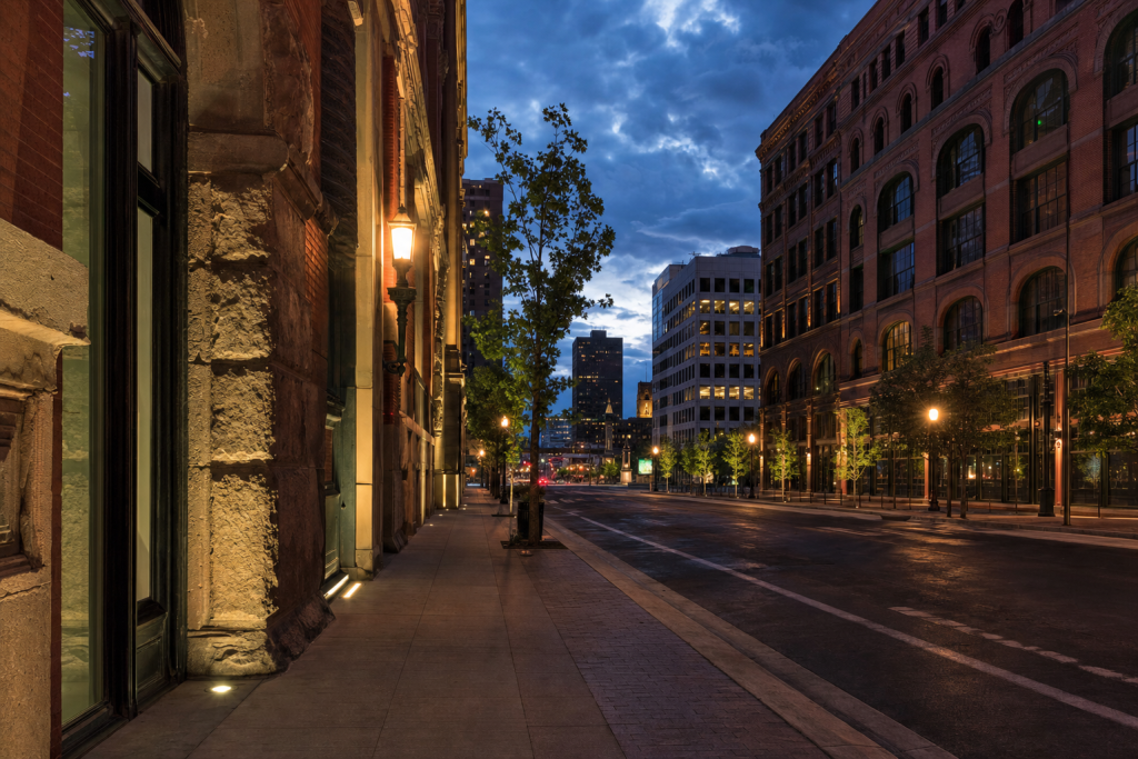 Street-level perspective in Denver, leading lines, architectural detail, blue hour with mixed ambient and street lighting