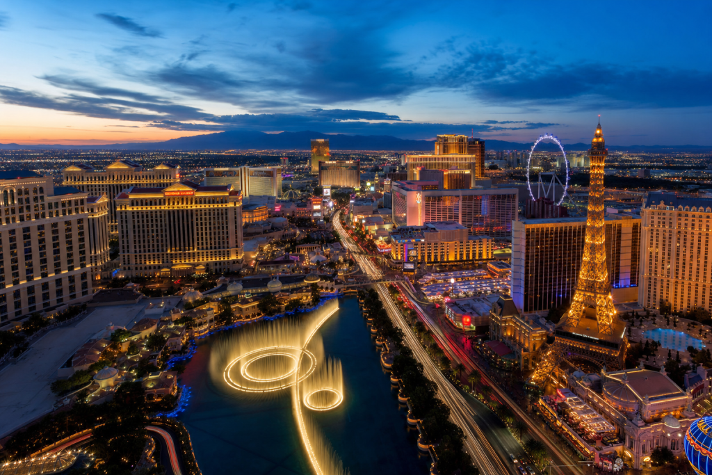 High-vantage view of Las Vegas during blue hour, glowing city lights, subtle motion blur in traffic