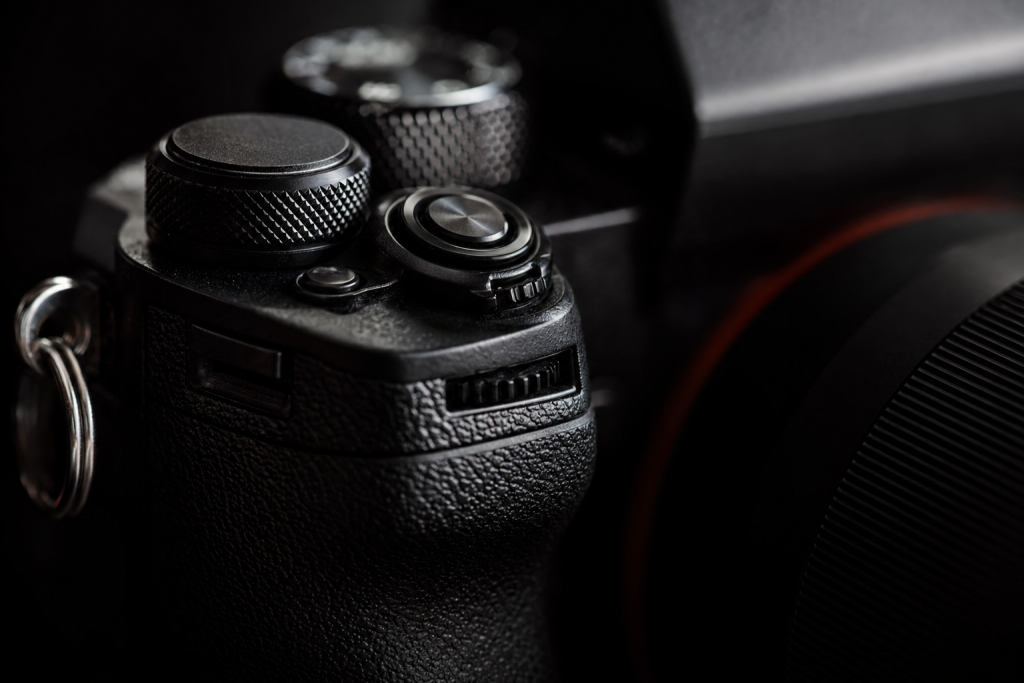 Detail shot of camera controls and grip, dramatic side lighting, macro feel, no text