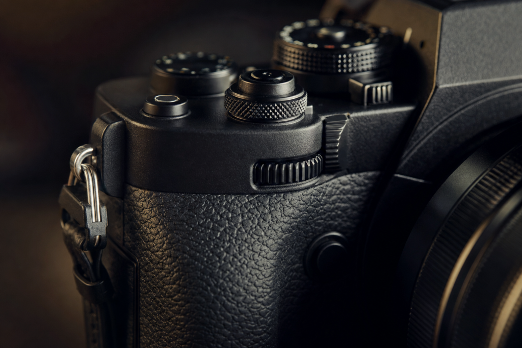 Detail shot of camera controls and grip, dramatic side lighting, macro feel, no text