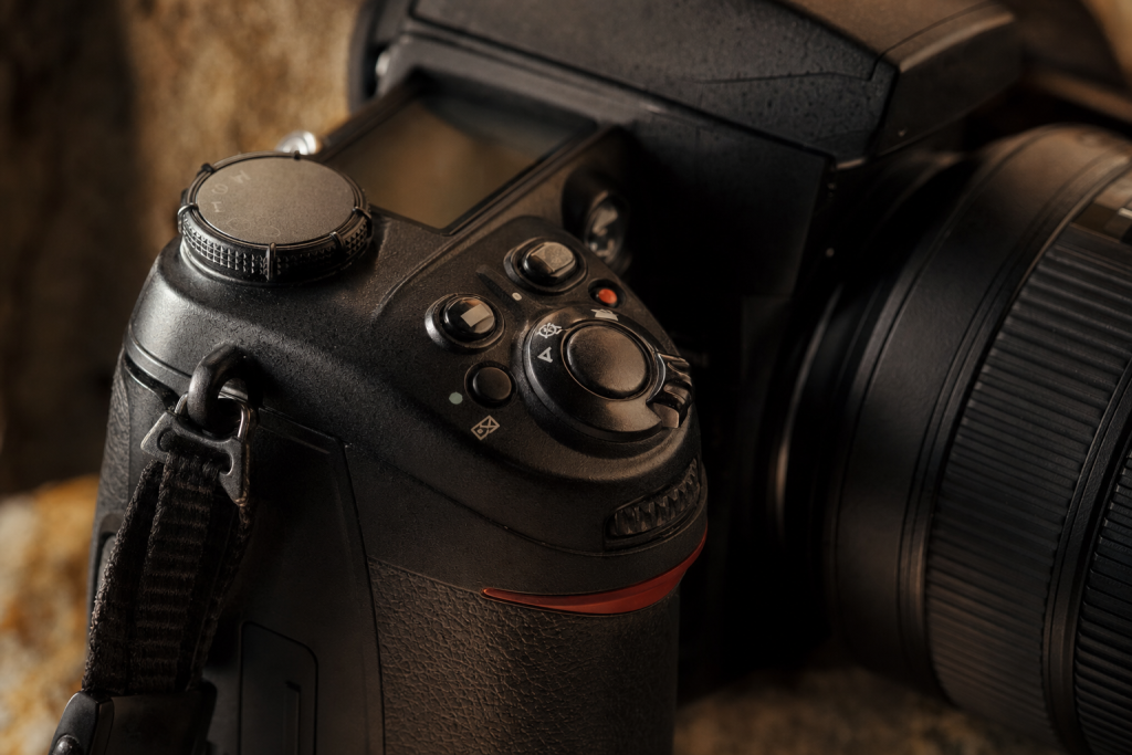 Detail shot of camera controls and grip, dramatic side lighting, macro feel, no text