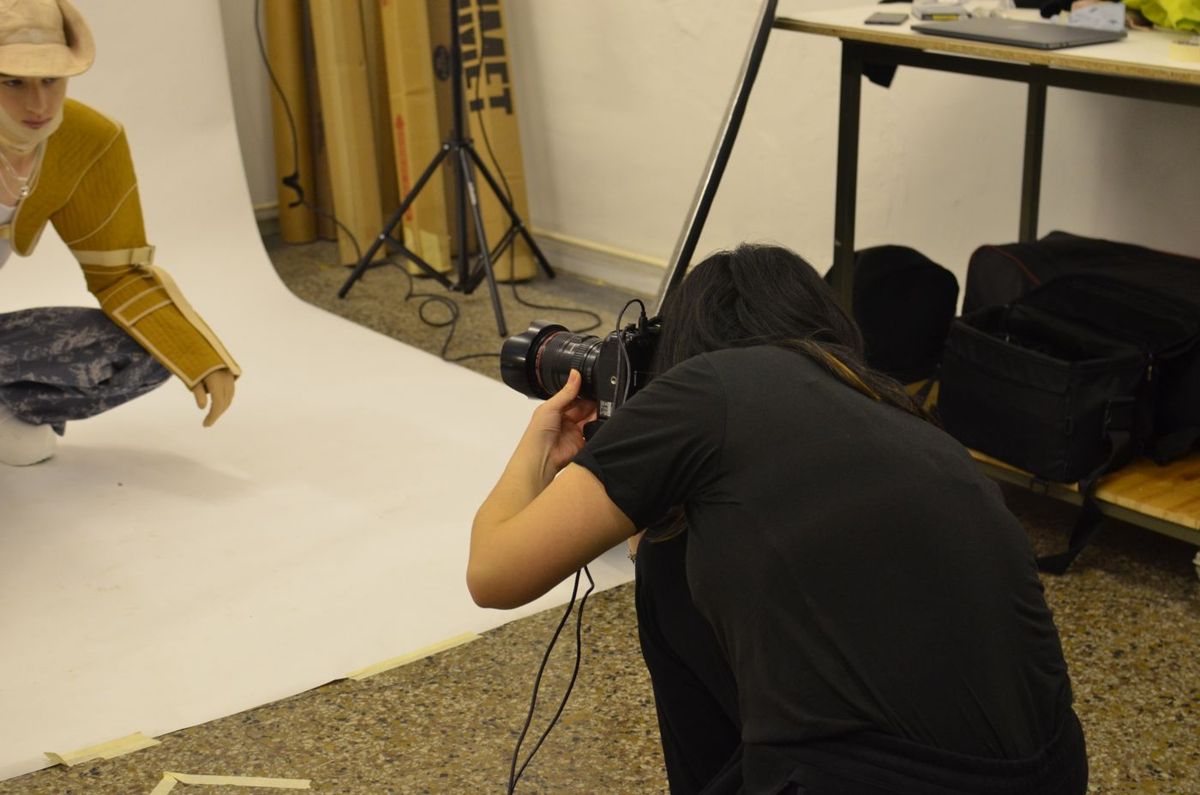 Photographer using a camera to photograph a model on a white studio sweep, behind-the-scenes example