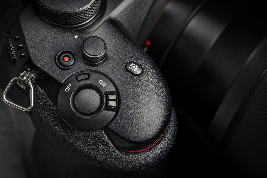 Detail shot of camera controls and grip, dramatic side lighting, macro feel, no text
