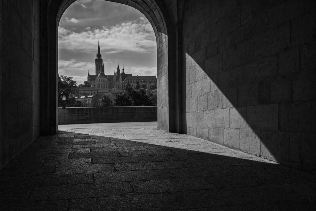 Black-and-white style street composition with strong geometric shadows, high contrast, decisive moment feel