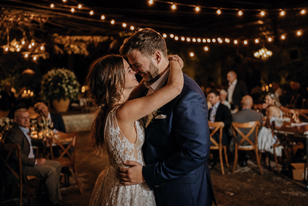 Candid wedding reception moment, warm string lights, joyful expressions, natural editorial color