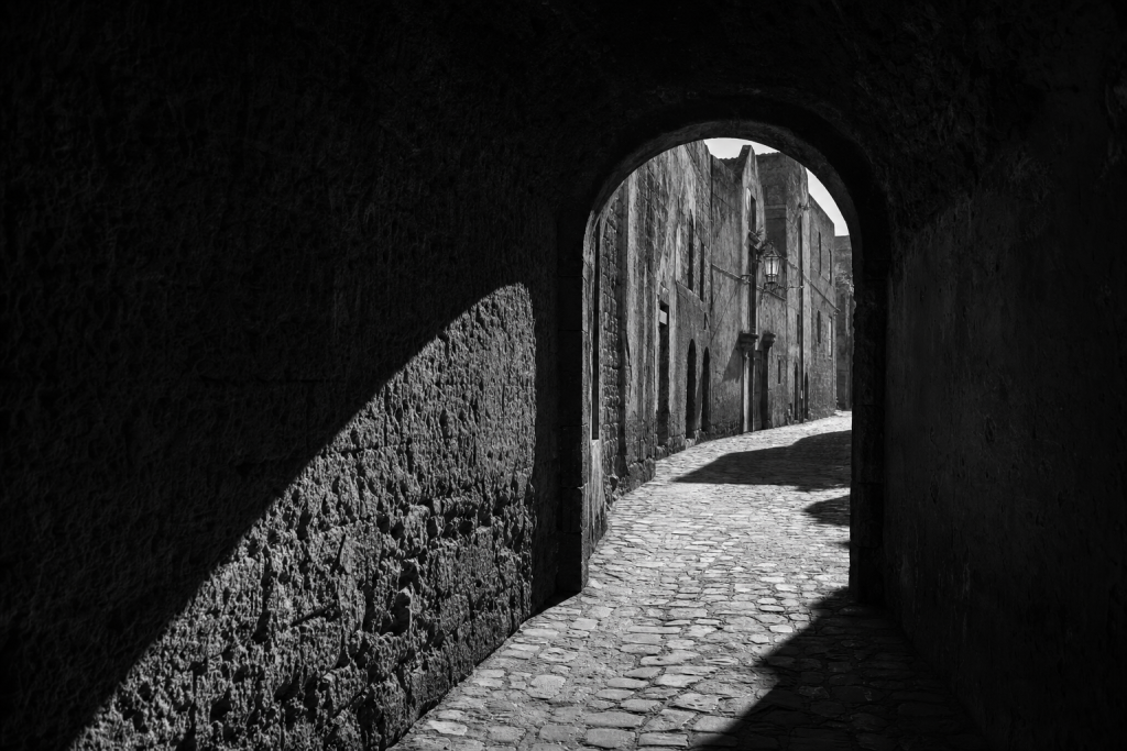 Black-and-white style street composition with strong geometric shadows, high contrast, decisive moment feel
