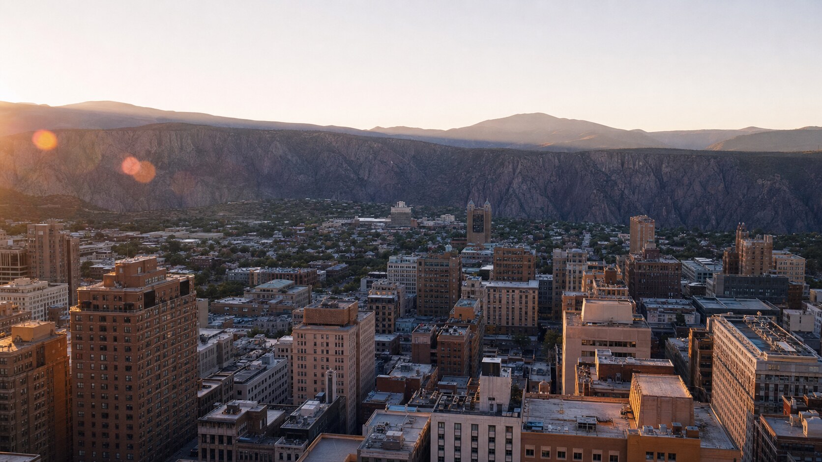 Elevated rooftop view of Black Canyon Of The Gunnison at golden hour, showing layered urban density and natural shadow direction
