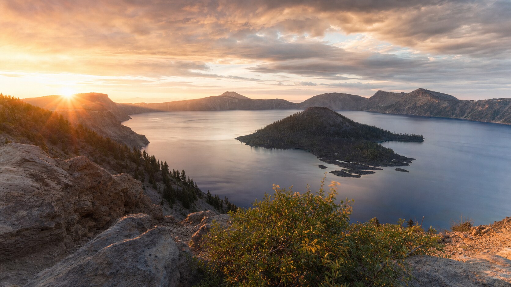 Sunrise landscape photograph at Crater Lake National Park from the most popular sunrise overlook, showing the signature foreground-to-background composition