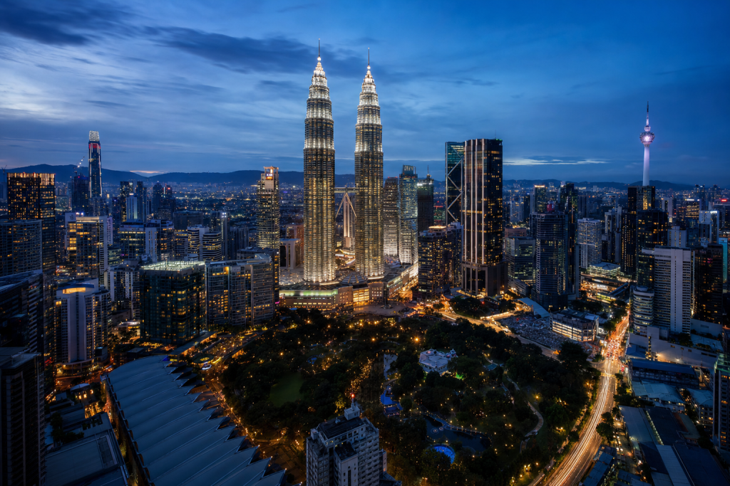 High-vantage view of Kuala Lumpur during blue hour, glowing city lights, subtle motion blur in traffic, long expo