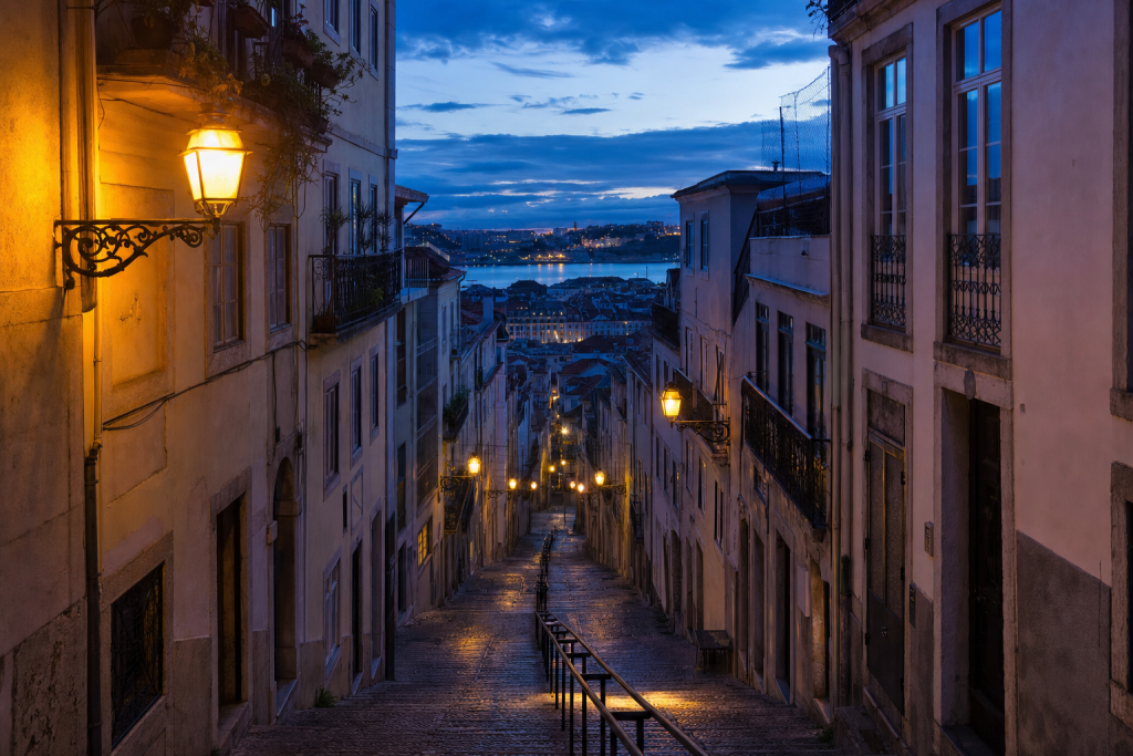 Street-level perspective in Lisbon, leading lines, architectural detail, blue hour with mixed ambient and street lighting