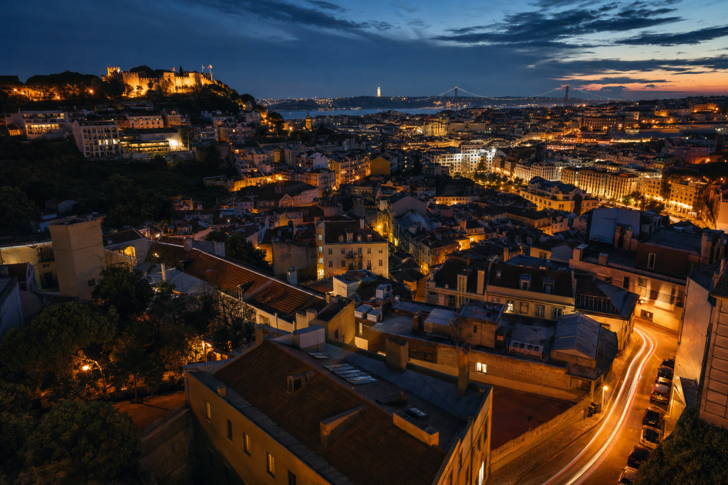 Atmospheric high-vantage view of Lisbon during blue hour, glowing city lights, subtle motion blur in traffic