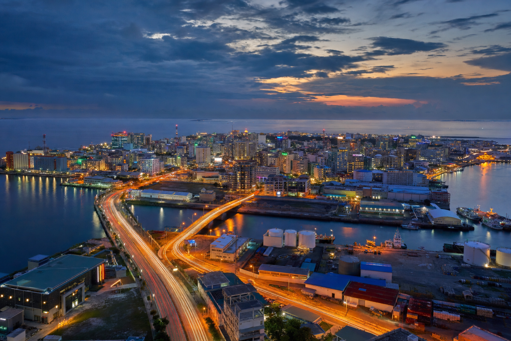 Male high-vantage cityscape at blue hour with city lights and traffic motion
