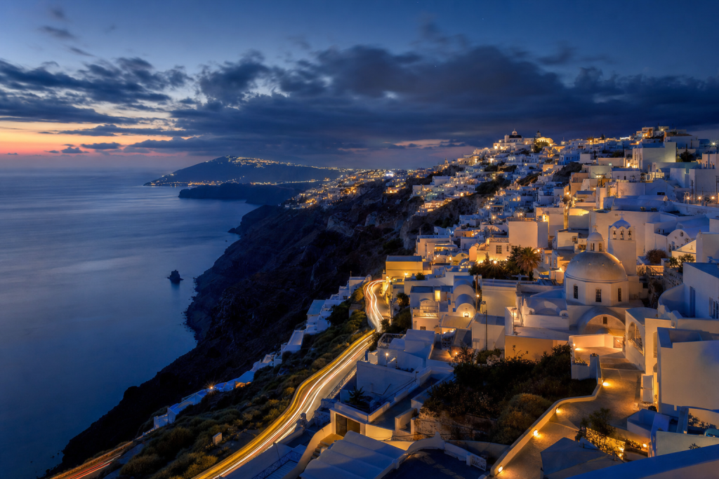 Santorini high-vantage cityscape at blue hour with city lights and traffic motion