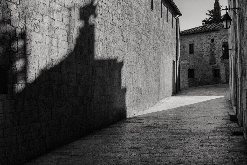 Black-and-white style street composition with strong geometric shadows, high contrast, decisive moment feel
