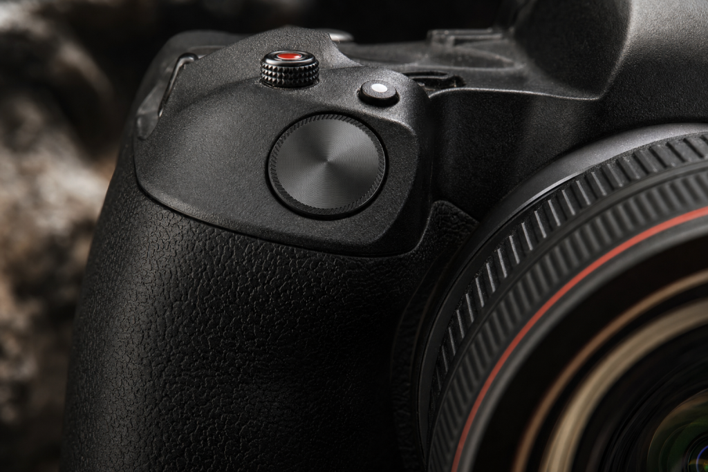 Detail shot of camera controls and grip, dramatic side lighting, macro feel, no text
