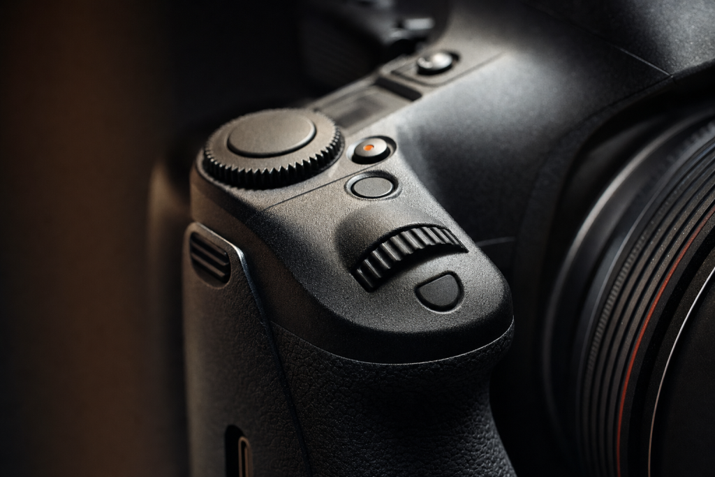 Detail shot of camera controls and grip, dramatic side lighting, macro feel, no text
