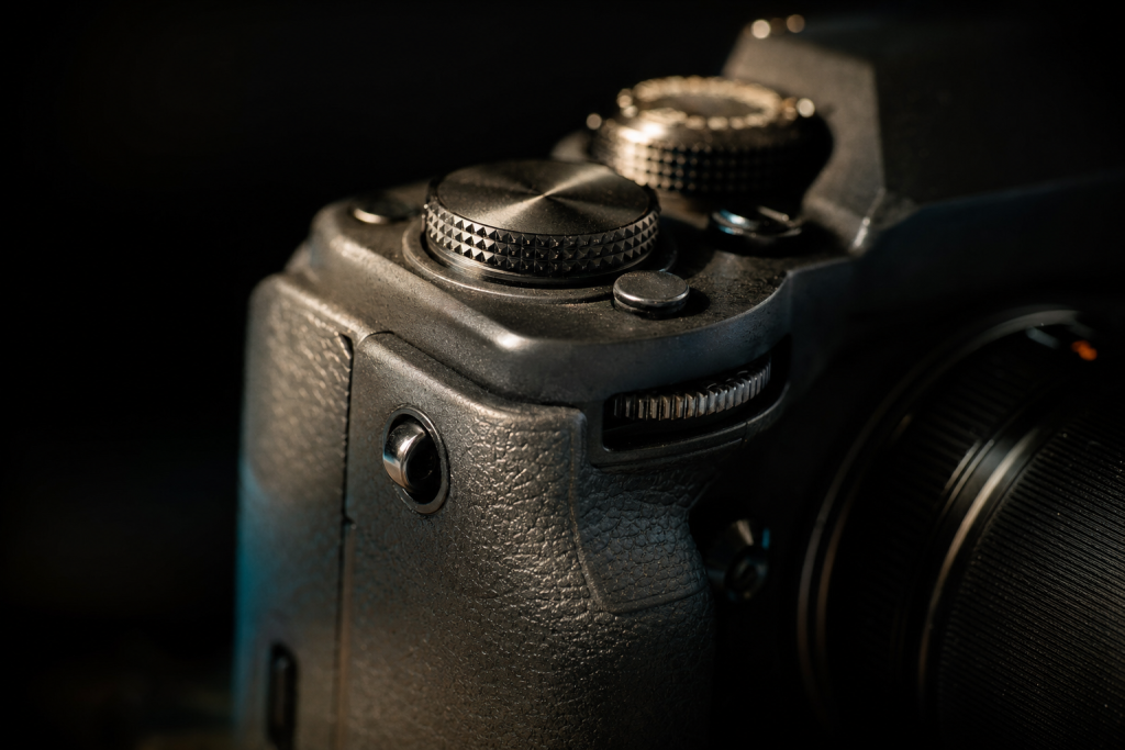 Detail shot of camera controls and grip, dramatic side lighting, macro feel, no text