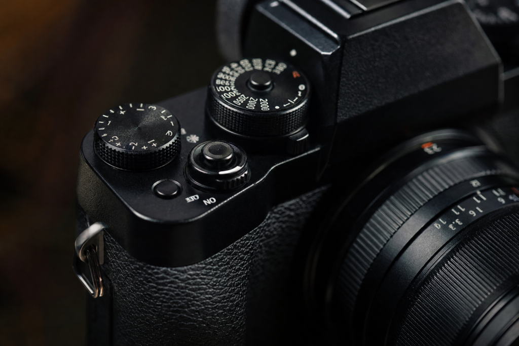 Detail shot of camera controls and grip, dramatic side lighting, macro feel, no text