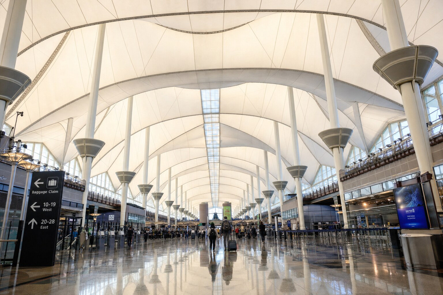 Jeppesen Terminal Great Hall interior at DEN with glowing tensile-fabric peaks overhead and polished granite floor