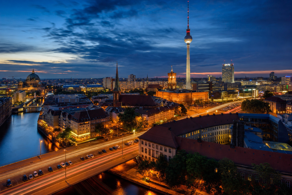 High-vantage view of Es Best Photography Spots in Berlin during blue hour, glowing city lights, subtle motion