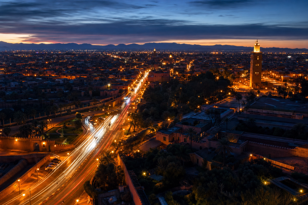 High-vantage view of Es Best Photography Spots in Marrakech during blue hour, glowing city lights, subtle motion