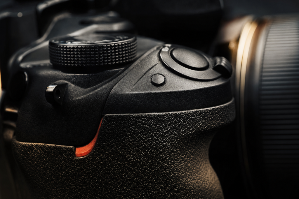 Detail shot of camera controls and grip, dramatic side lighting, macro feel, no text
