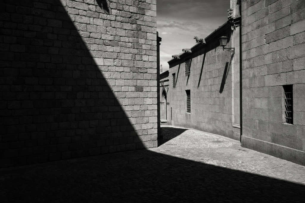Black-and-white style street composition with strong geometric shadows, high contrast, decisive moment feel