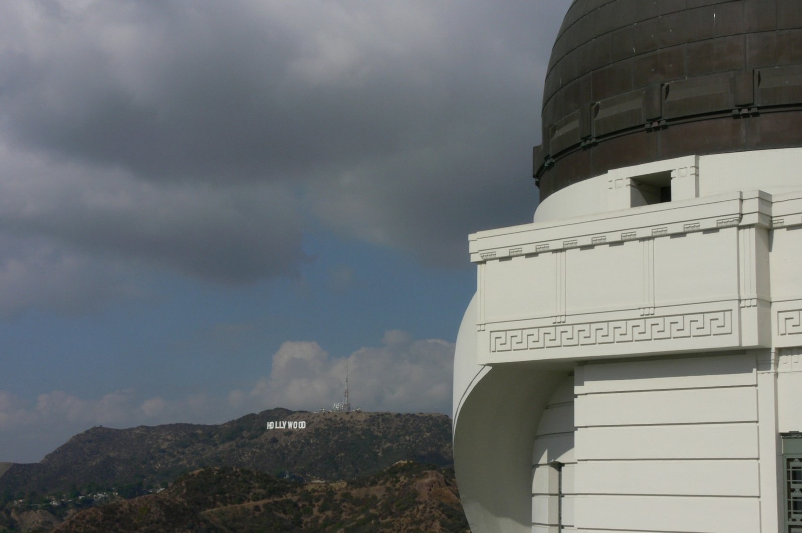 Hollywood Sign visible behind the copper-domed Griffith Observatory rotunda on Mount Hollywood in Los Angeles, photographed from the western terrace