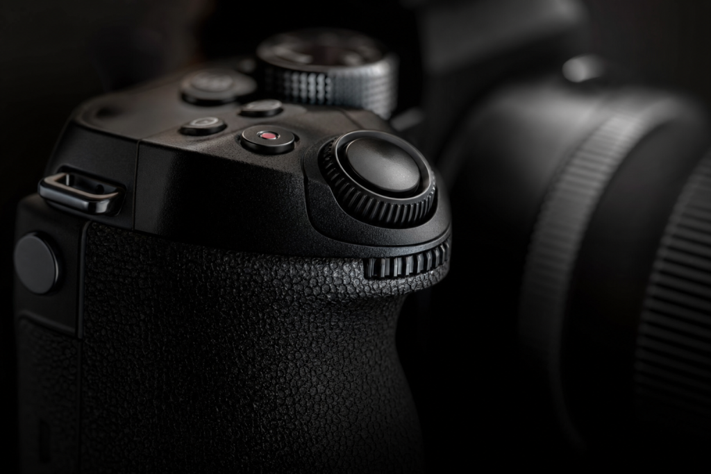 Detail shot of camera controls and grip, dramatic side lighting, macro feel, no text