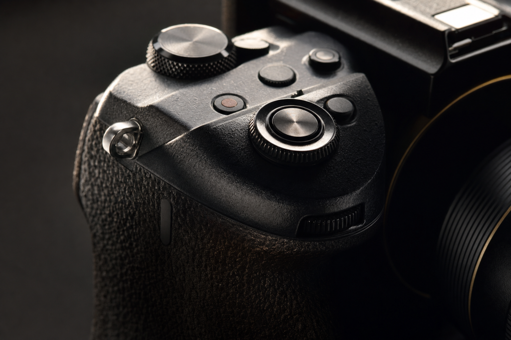 Detail shot of camera controls and grip, dramatic side lighting, macro feel, no text