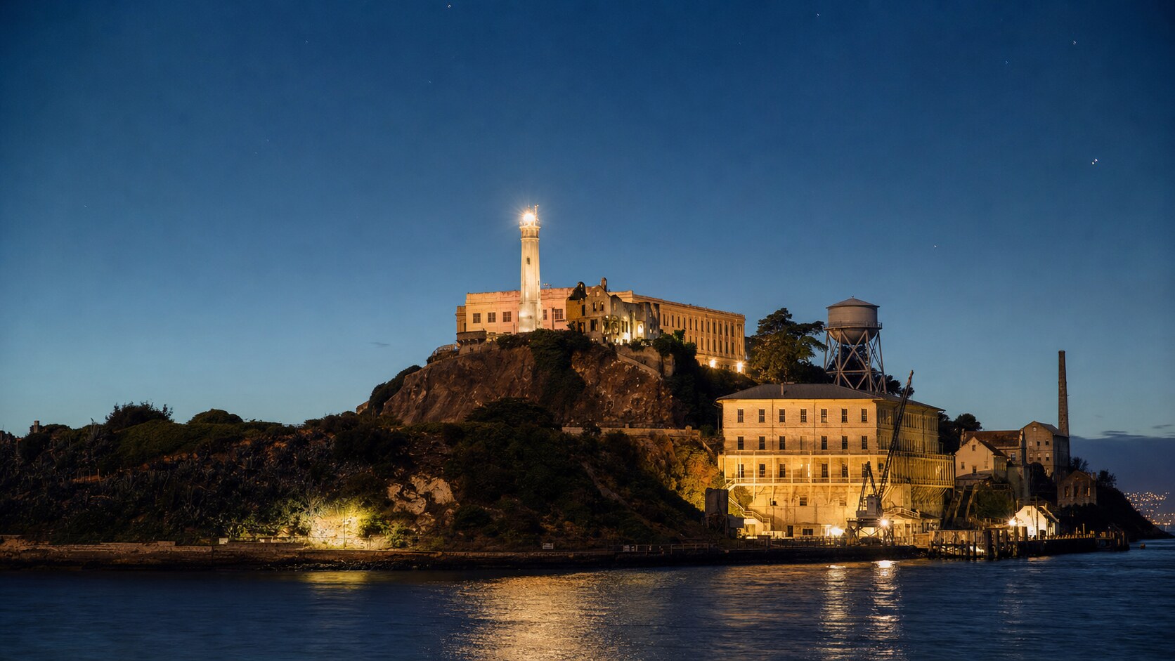 Wide blue-hour view of Alcatraz Island with cobalt sky and warm artificial lighting on the landmark