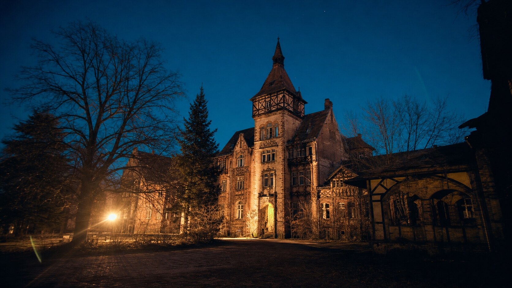 Wide blue-hour view of Beelitz Heilstatten with cobalt sky and warm artificial lighting on the landmark