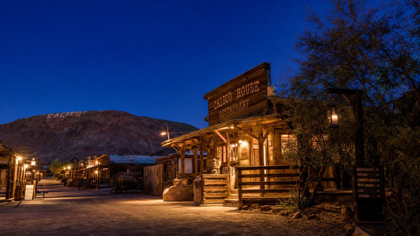 Wide blue-hour view of Calico Ghost Town with cobalt sky and warm artificial lighting on the landmark