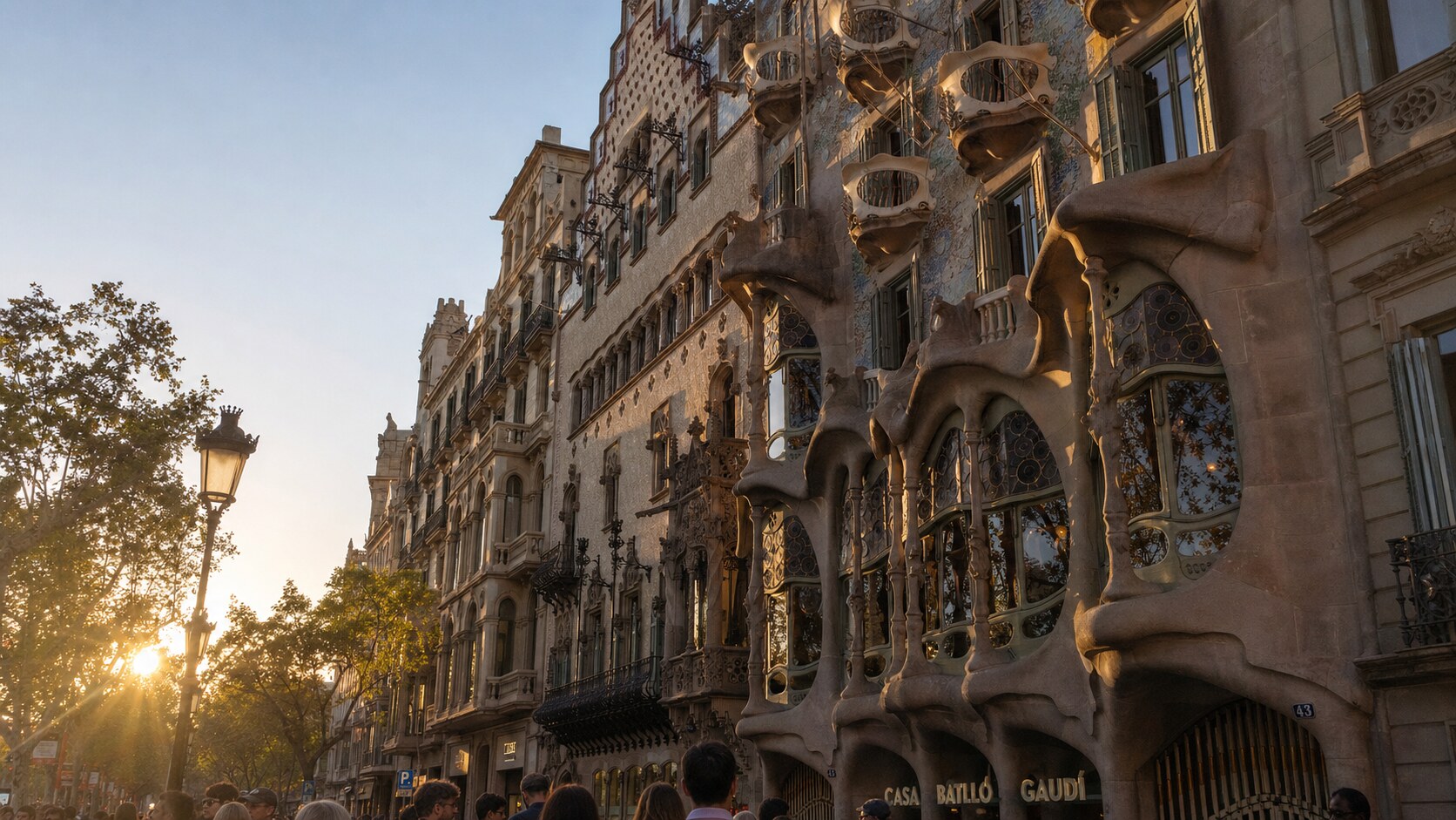 Casa Batllo photographed at golden hour from the most popular hero-shot vantage point, with dramatic side-lighting on the structure