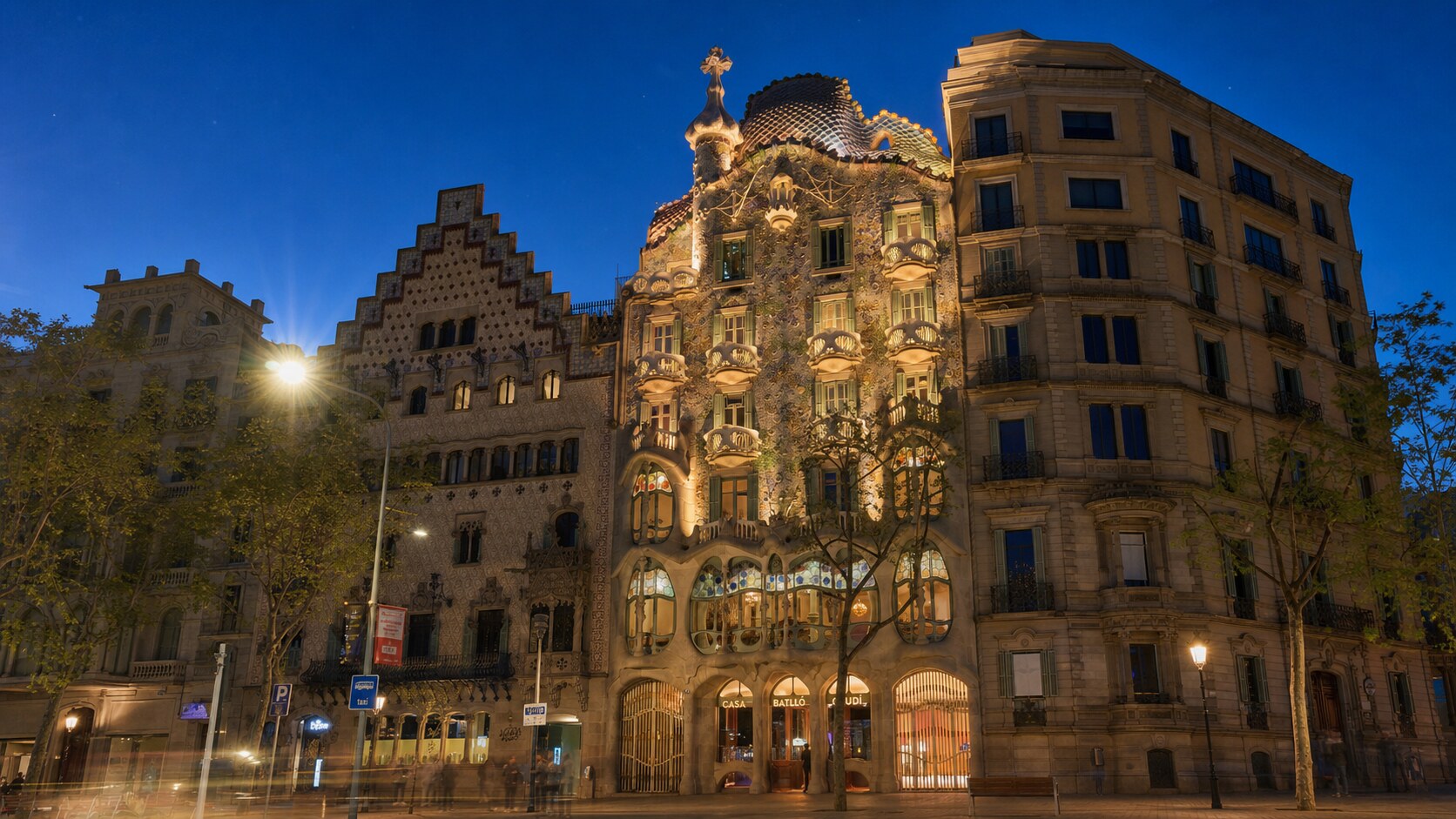 Wide blue-hour view of Casa Batllo with cobalt sky and warm artificial lighting on the landmark