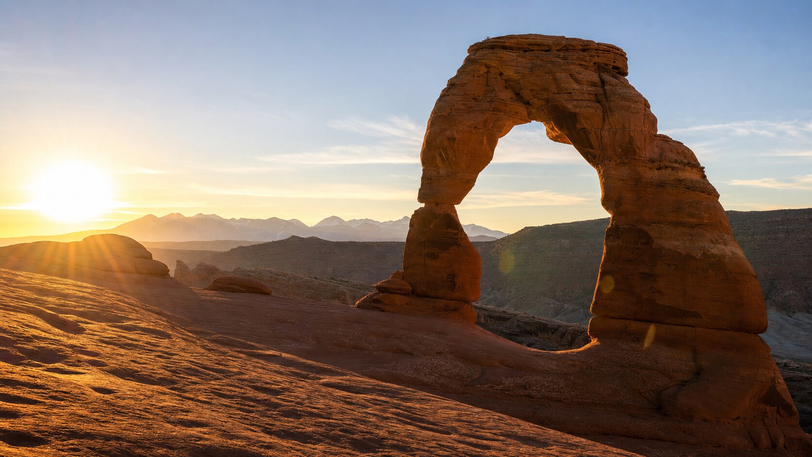 Delicate Arch photographed at golden hour from the most popular hero-shot vantage point, with dramatic side-lighting on the structure