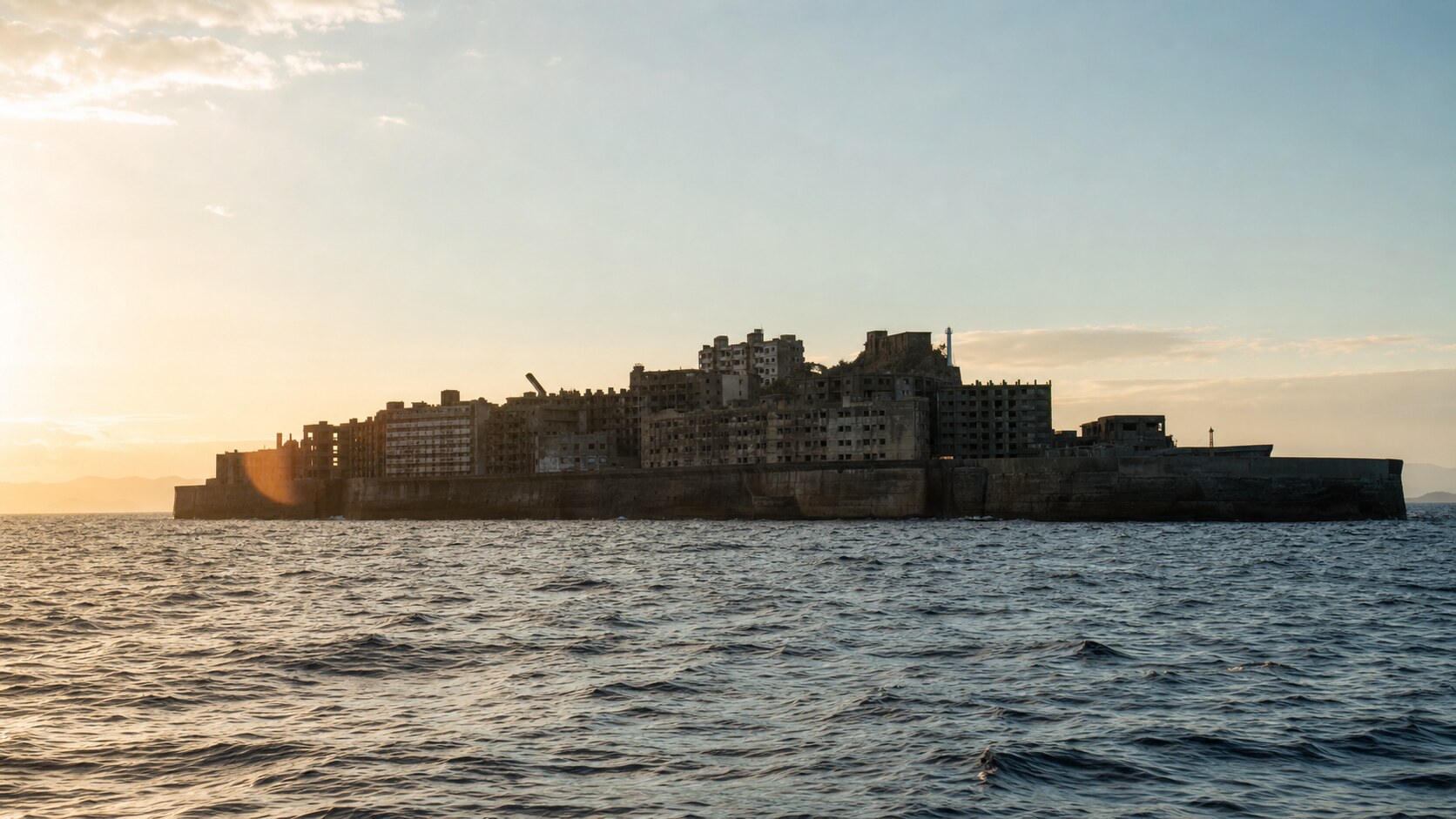Hashima Battleship Island photographed at golden hour from the most popular hero-shot vantage point, with dramatic side-lighting on the structure