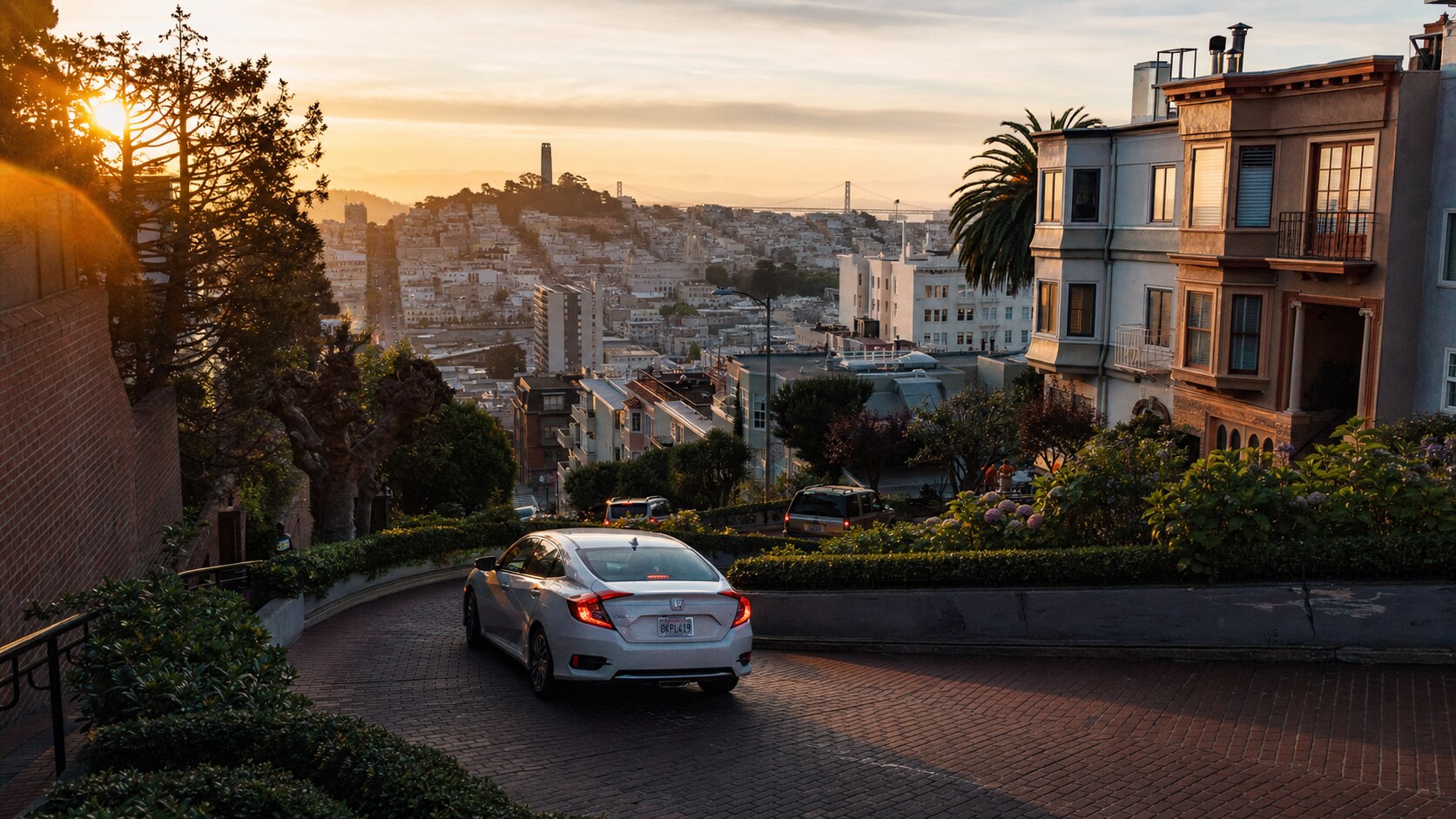 Lombard Street photographed at golden hour from the most popular hero-shot vantage point, with dramatic side-lighting on the structure