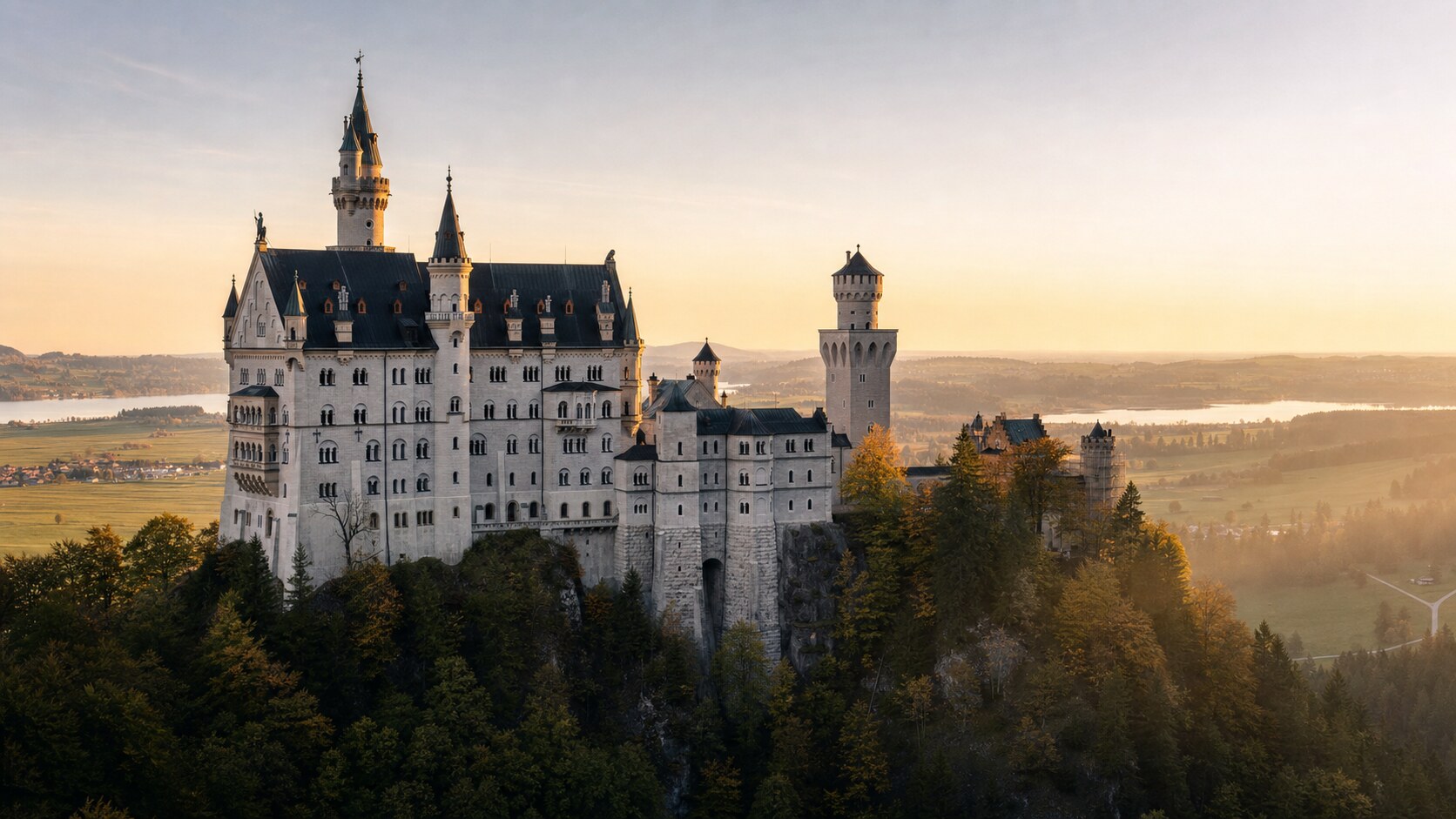 Neuschwanstein Castle photographed at golden hour from the most popular hero-shot vantage point, with dramatic side-lighting on the structure