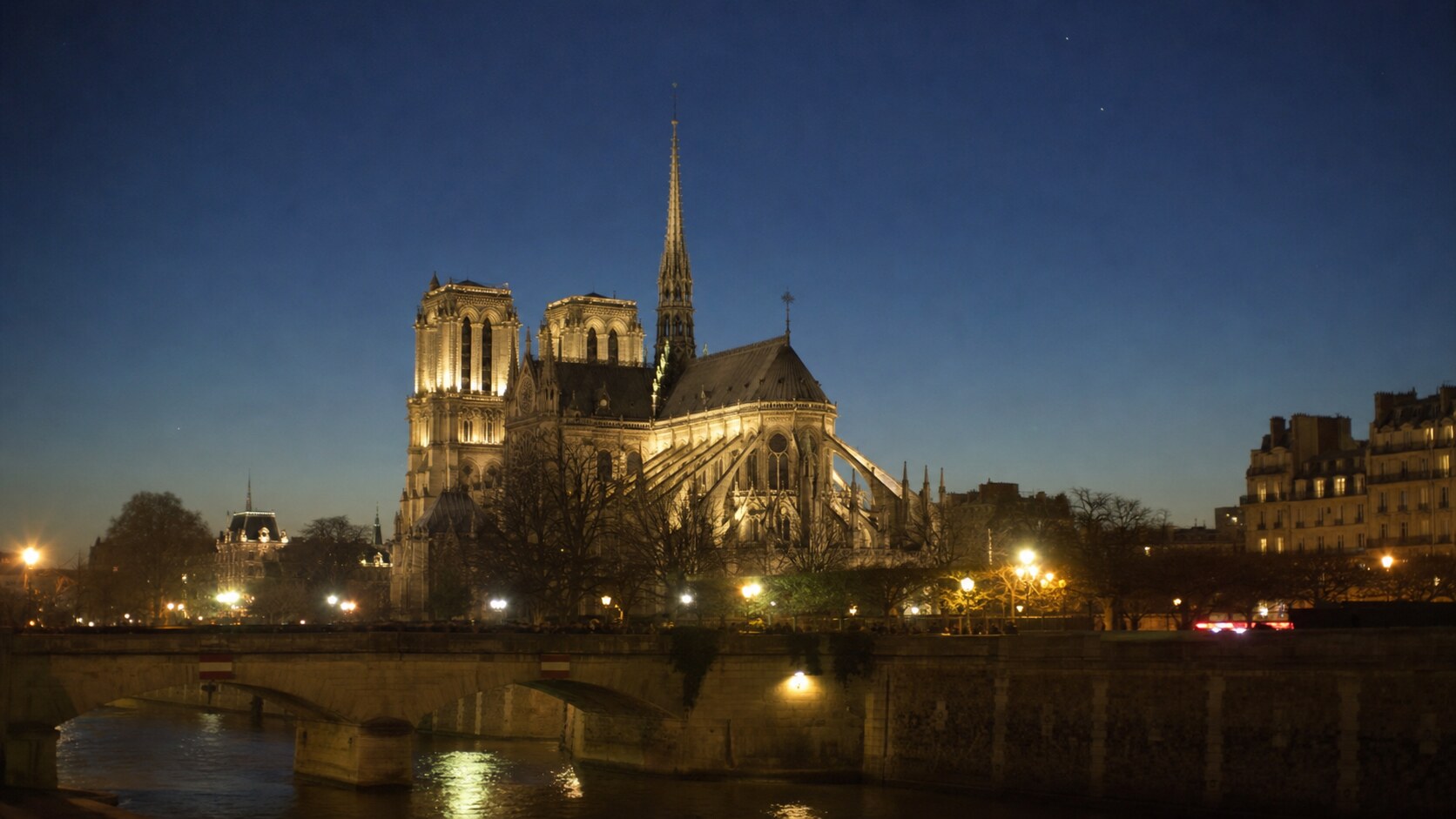 Wide blue-hour view of Notre Dame Paris with cobalt sky and warm artificial lighting on the landmark