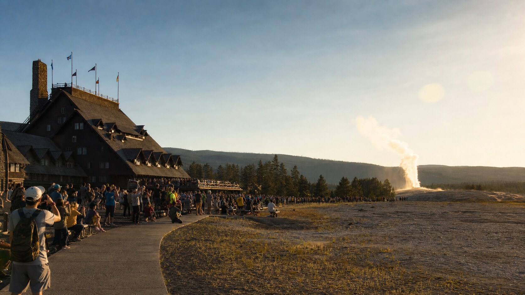 Old Faithful photographed at golden hour from the most popular hero-shot vantage point, with dramatic side-lighting on the structure